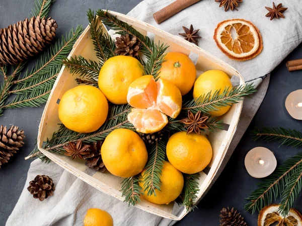 Bir köknar ağacının dalları ile ahşap sepeti, yıldız anason tarçın gri arka plan üzerinde taze mandalina