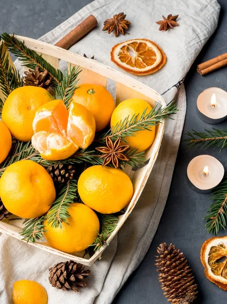 Bir köknar ağacının dalları ile ahşap sepeti, yıldız anason tarçın gri arka plan üzerinde taze mandalina