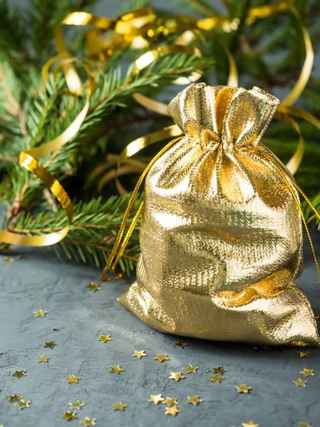 Ветки ели на сером бетонном фоне с золотыми звездами. Новое Рождество. Золотая сумка с подарками — стоковое фото