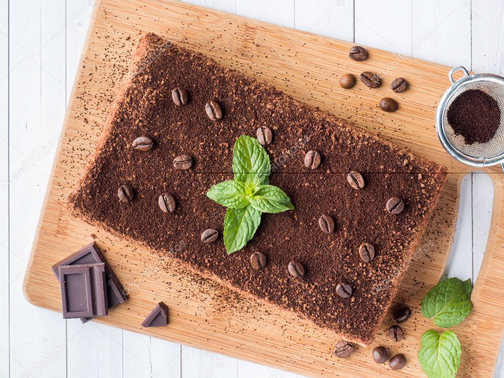Tiramisu cake with coffee beans and fresh mint chocolate on the Board in white background Close up