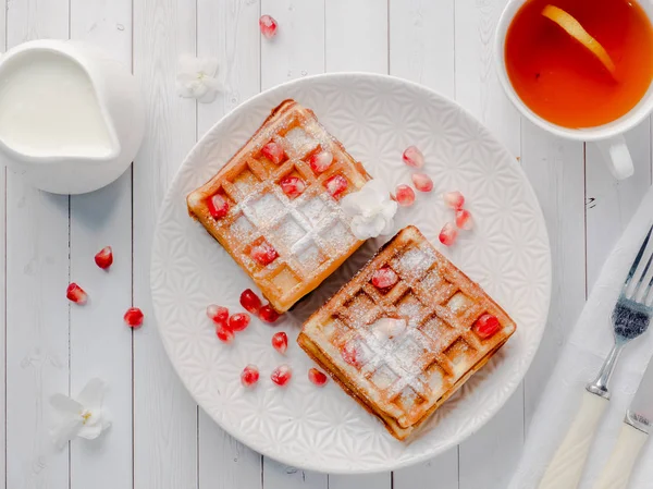 Köstliche Wiener Waffeln mit Honig und Granatapfelkernen auf weißem Teller, heller Holzgrund — Stockfoto