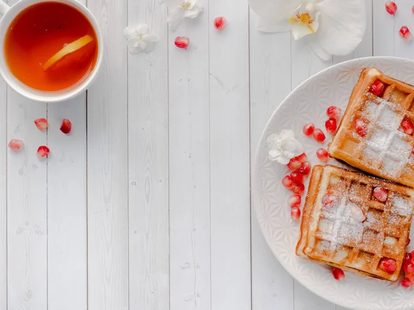 Köstliche köstliche Wiener Waffeln mit Honig und Granatapfelkernen auf einem weißen Teller, heller Holzhintergrund Kopierraum — Stockfoto
