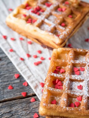 Pudra şekeri ve rustik ahşap arka plan üzerinde kırmızı kalpler ile yumuşak Viyana Belçika waffle