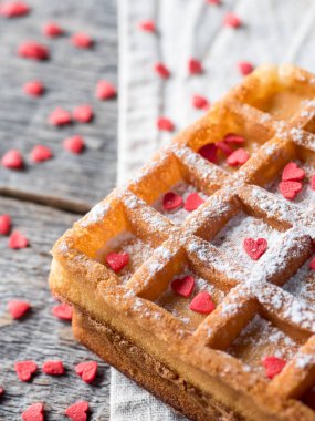 Pudra şekeri ve rustik ahşap arka plan üzerinde kırmızı kalpler ile yumuşak Viyana Belçika waffle