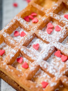 Pudra şekeri ve rustik ahşap arka plan üzerinde kırmızı kalpler ile yumuşak Viyana Belçika waffle