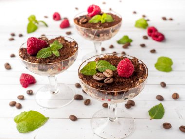 Cam kadehi naneli kahve çekirdekleri ve Beyaz ahşap masa üzerinde taze ahududu tatlı Tiramisu