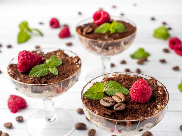 Postre Tiramisú en copa de vidrio con granos de café de menta y frambuesas frescas en mesa de madera blanca —  Fotos de Stock