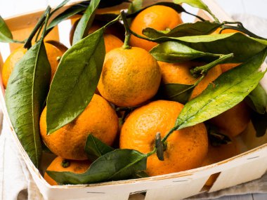 Taze mandalina veya mandalina sapları ve yaprakları Beyaz ahşap zemin üzerindeki kutuda ile