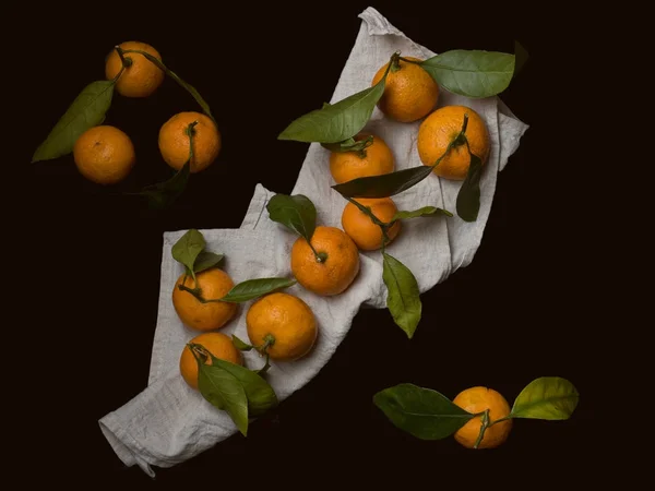 Mandarin segar atau jeruk keprok dengan batang dan daun pada latar belakang kayu hitam . — Stok Foto