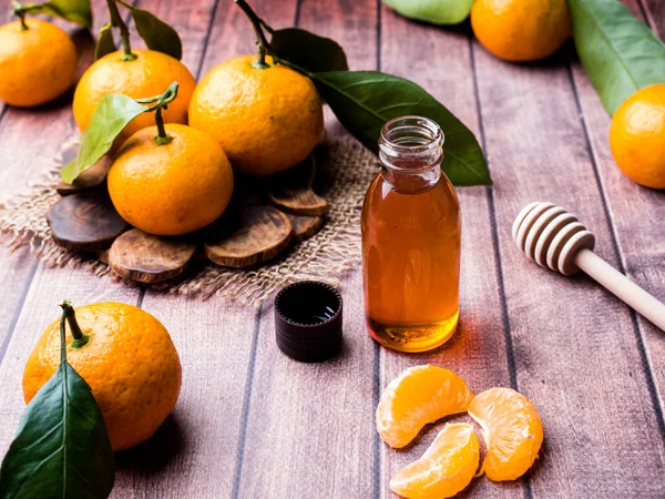 Ароматическое мандариновое масло, с мандаринами на деревянном фоне, избирательный фокус — стоковое фото