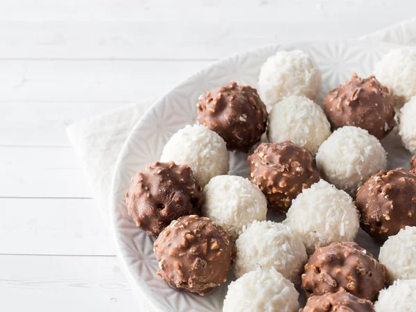 Chocolate e doce de coco em uma placa de fundo branco — Fotografia de Stock