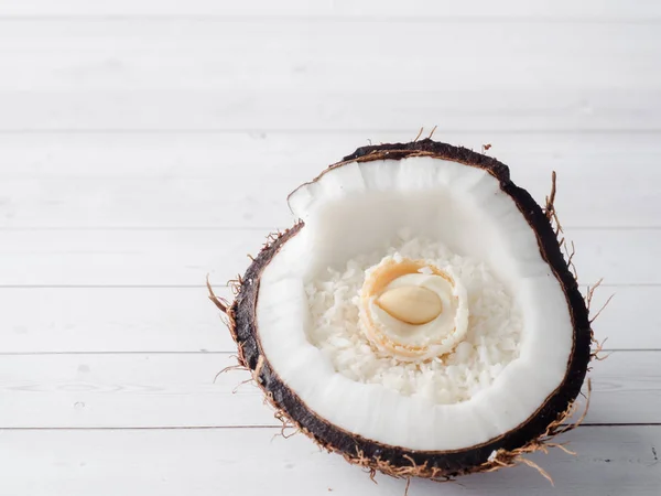 Hälften av färsk ekologisk kokos med kokos och choklad godis inne på trä bakgrund — Stockfoto