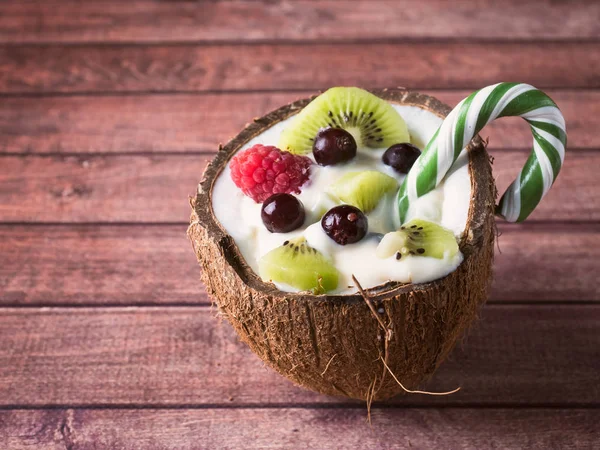 Fruchtjoghurt in den Kokosnusshälften mit frischen Beeren auf dunklem Holzgrund — Stockfoto