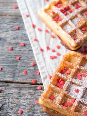 Pudra şekeri ve rustik ahşap arka plan kopya alanı üzerinde kırmızı kalpler ile yumuşak Viyana Belçika waffle