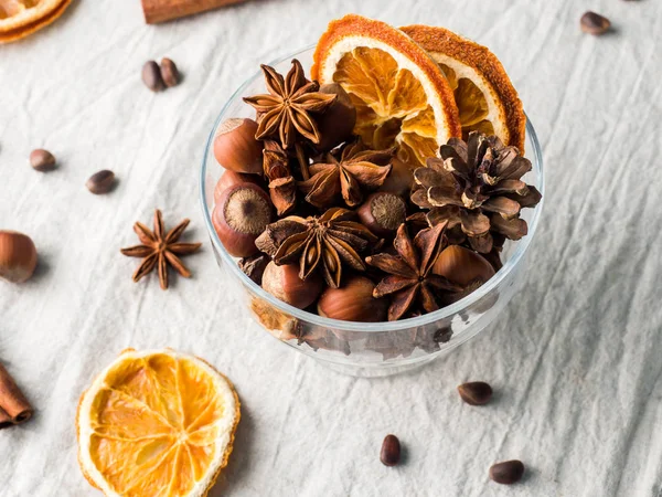 Winter ingredients nuts, cones, oranges, cinnamon star anise in a bowl. Rustic style — Stock Photo, Image