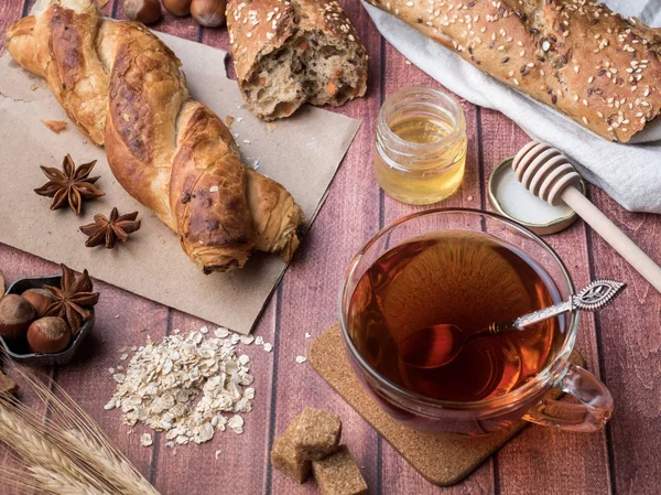 Pan de grano con miel y nueces, una taza de té de azúcar morena sobre fondo de madera oscura — Foto de Stock