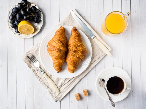 Frukost på en vit tabell kaffe Croissant Orange juice druvor Apple choklad — Stockfoto