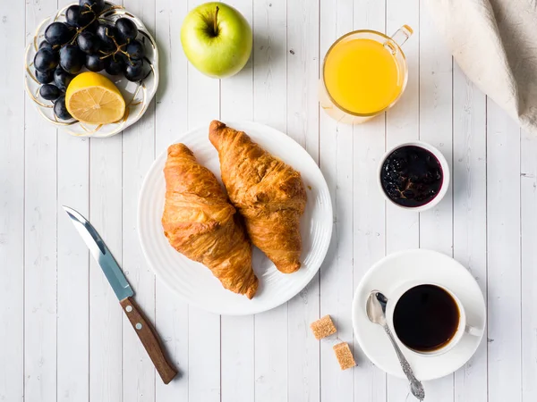 Desayuno en una mesa blanca Café Croissant Zumo de naranja Uvas Chocolate de manzana — Foto de Stock