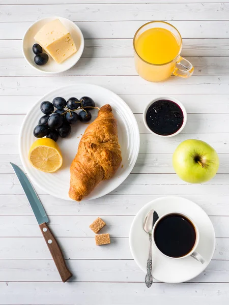 Desayuno en una mesa blanca Café Croissant Zumo de naranja Uvas Chocolate de manzana — Foto de Stock