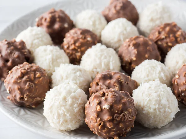 Chocolate y caramelo de coco en una placa de fondo blanco —  Fotos de Stock