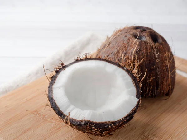 Fresh organic coconut broken into two parts on rustic wooden background