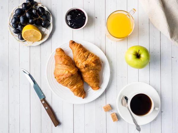 Desayuno en una mesa blanca Café Croissant Zumo de naranja Uvas Chocolate de manzana — Foto de Stock