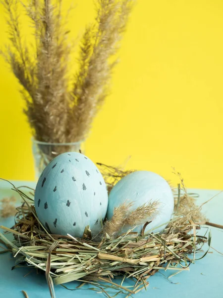 Uova di Pasqua in un nido d'erba. sfondo giallo . — Foto Stock