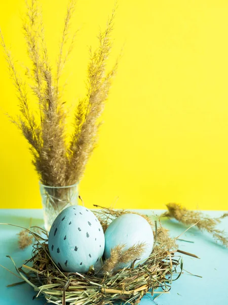 Uova di Pasqua in un nido d'erba. sfondo giallo . — Foto Stock