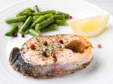 Sağlıklı gıda. Pişmiş kırmızı balık, Pembe somon, somon ve yeşil fasulye bir dilim limon bir plaka üzerinde.