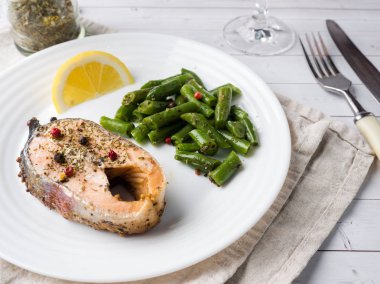 Sağlıklı gıda. Pişmiş kırmızı balık, Pembe somon, somon ve yeşil fasulye bir dilim limon bir plaka üzerinde.