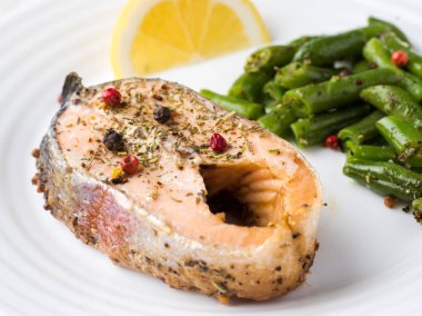 Sağlıklı gıda. Pişmiş kırmızı balık, Pembe somon, somon ve yeşil fasulye bir dilim limon bir plaka üzerinde.