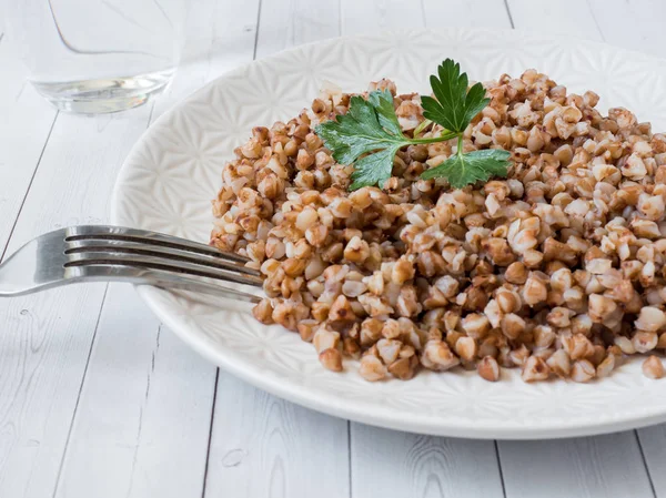 Gachas de trigo sarraceno con hojas de perejil en un plato, comida saludable — Foto de Stock