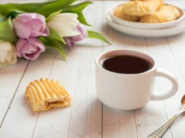 Bisküvi ve ahşap bir masa üzerinde Lale ile kahve fincanı