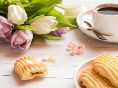 Bisküvi ve ahşap bir masa üzerinde Lale ile kahve fincanı