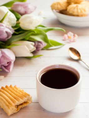 Bisküvi ve ahşap bir masa üzerinde Lale ile kahve fincanı