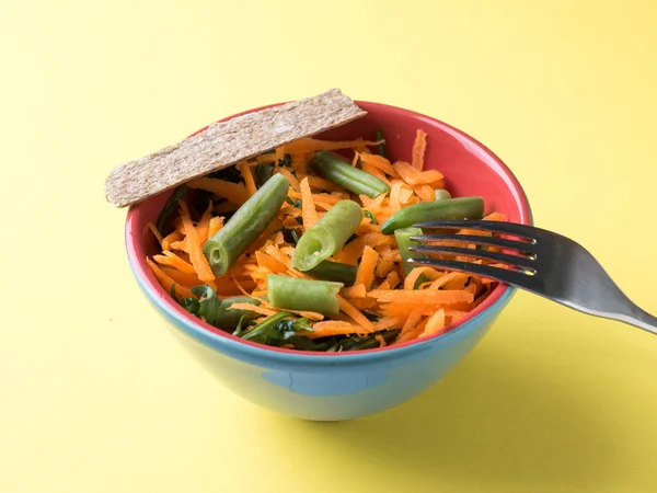 Здоровий салат з тертої моркви зеленої боби рукола на жовтому фоні — стокове фото