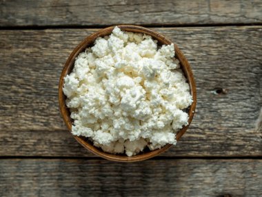 Eski ahşap masa ahşap bir kabın içinde ev yapımı peynir.