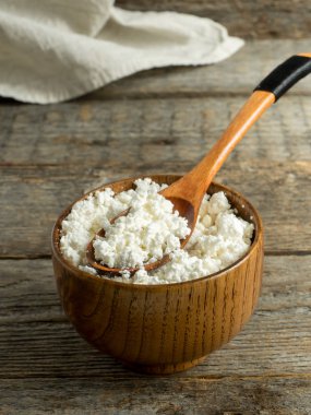 Ev yapımı peynir rustik ahşap bir masa üzerinde bir kaşıkla bir ahşap kase.