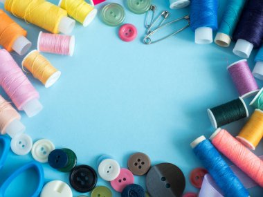 Düz yatıyordu çok renkli dikiş ipliği ve kopya alanı ile mavi arka plan düğmeleri