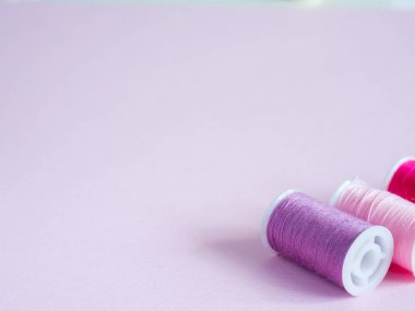 Renkli dikiş düğmeleri ve pembe bir arka plan iş parçacığında.