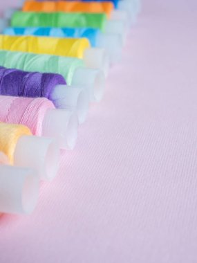 Renkli dikiş düğmeleri ve pembe bir arka plan iş parçacığında.