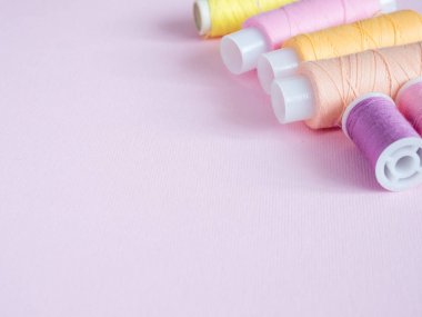 Renkli dikiş düğmeleri ve pembe bir arka plan iş parçacığında.