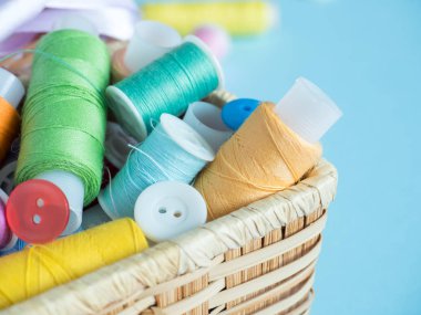 Renkli dikiş düğme ve bir ahşap kutu üzerinde mavi bir arka plan iş parçacığında.