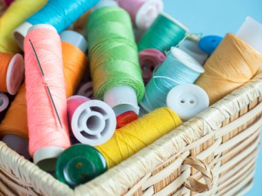 Renkli dikiş düğme ve bir ahşap kutu üzerinde mavi bir arka plan iş parçacığında.