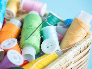 Renkli dikiş düğme ve bir ahşap kutu üzerinde mavi bir arka plan iş parçacığında.