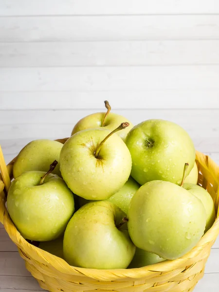 Grüne reife Äpfel in einem gelben Weidenkorb — Stockfoto