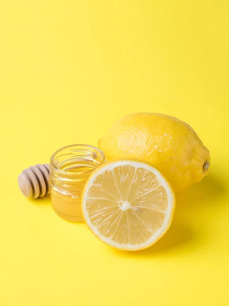 Un frasco de miel y limón fresco sobre un fondo amarillo brillante — Foto de Stock