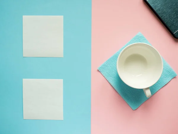 Business flat lay con spazio di copia su uno sfondo diviso in metà rosa e blu Quaderni per scrivere adesivi di testo Tazza bianca vuota — Foto Stock
