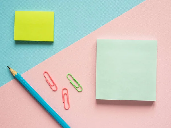 Business flat lay con espacio de copia sobre un fondo dividido en medio rosa y azul Cuadernos para escribir pegatinas de texto Lápiz, Papelería clip de papel de color . — Foto de Stock
