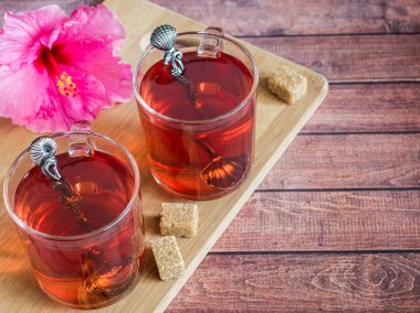 Cam fincan koyu ahşap arka plan üzerinde kırmızı çay pembe hibiscus çiçek